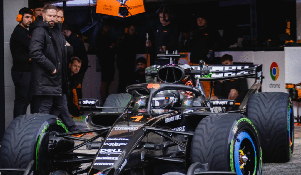 McLaren F1 team members observing the car in the garage during the Barcelona shakedown test following a fuel system issue.