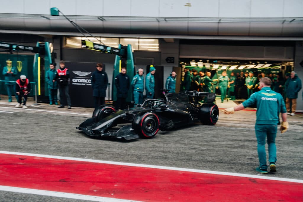 The Aston Martin F1 car exiting the garage at the Barcelona circuit, showcasing its radical 2026-cycle design and aggressive packaging during a test session.