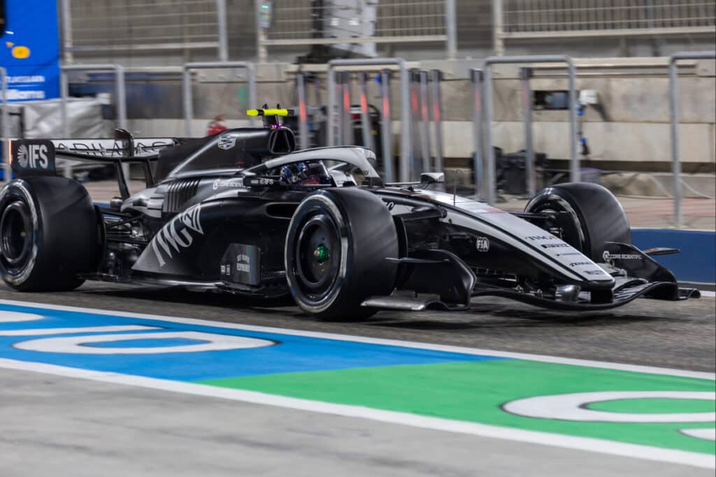 Side view of the Cadillac F1 car in motion during Bahrain testing, powered by a Ferrari engine.