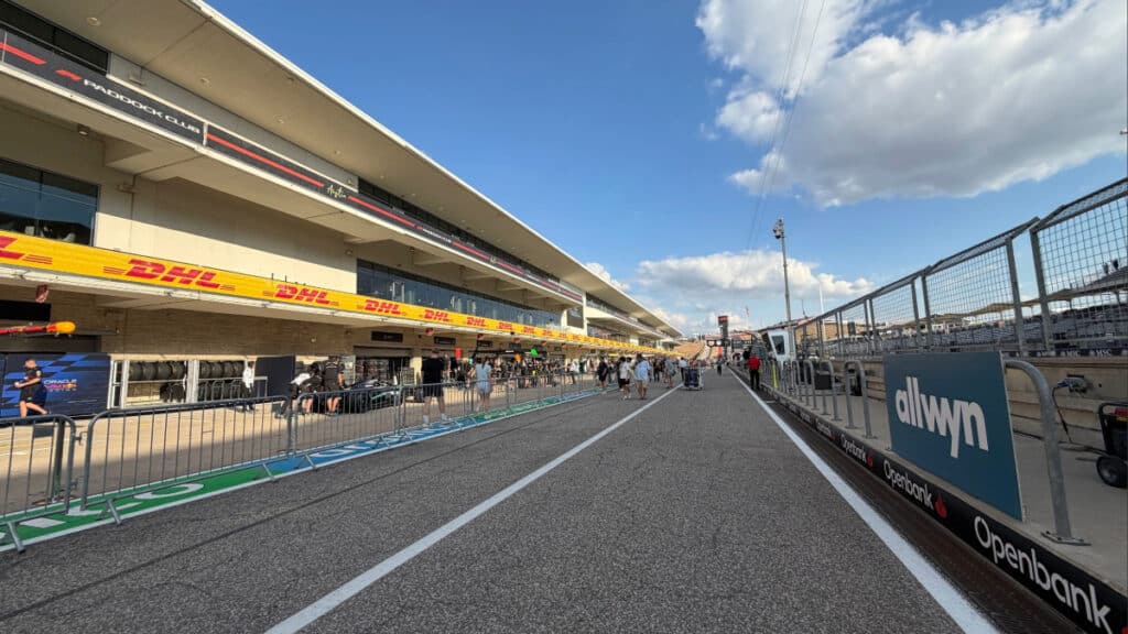 A wide-angle view of the Formula One pit lane and paddock under a blue sky, representing the strategic paths for future regulations.