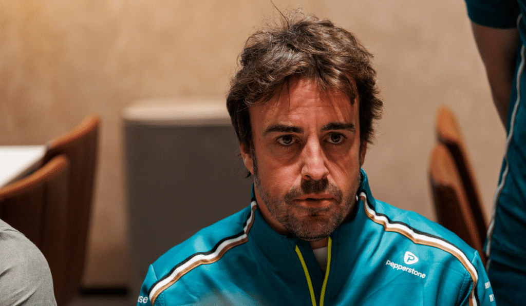 A close-up portrait of Fernando Alonso wearing his Aston Martin team kit, looking focused and pragmatic during the 2026 season preparations.