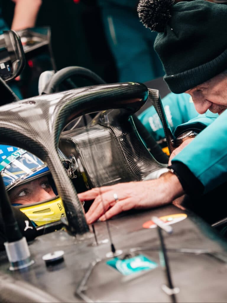 Close-up of Fernando Alonso in the Aston Martin cockpit, eyes visible through his visor, reflecting the intense focus and pressure of the team's 2026 development goals.