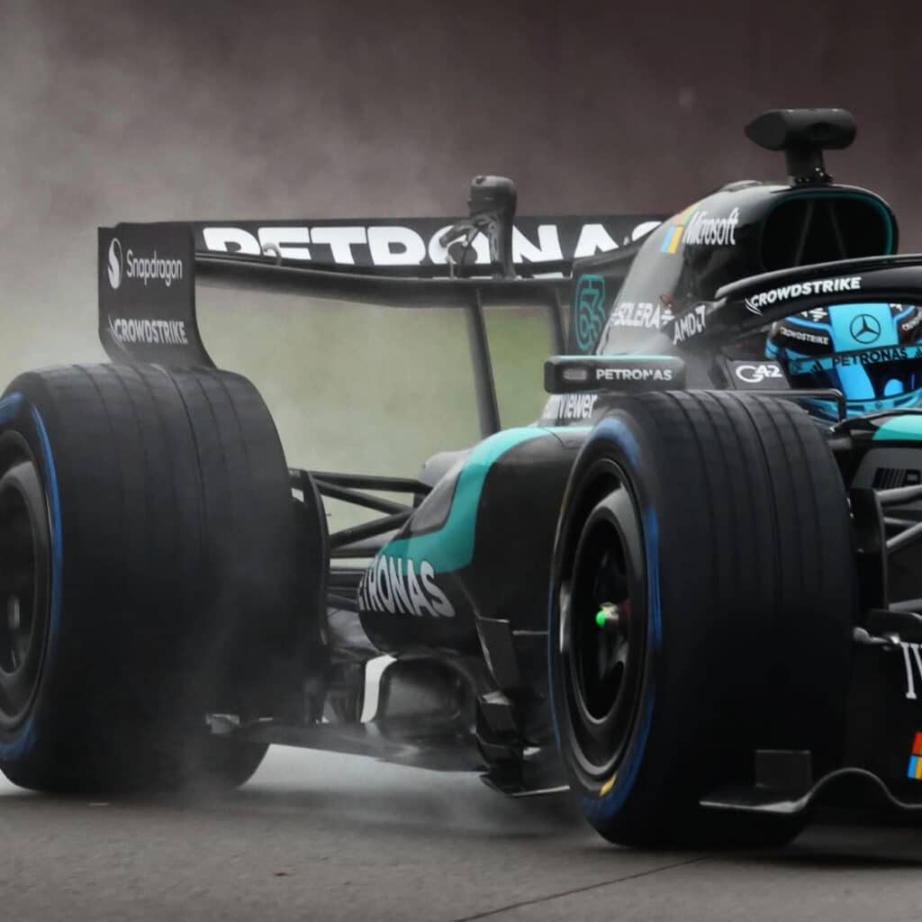 Close-up rear view of the Mercedes-AMG F1 car in motion during a damp testing session, symbolizing the mystery surrounding their true pace.