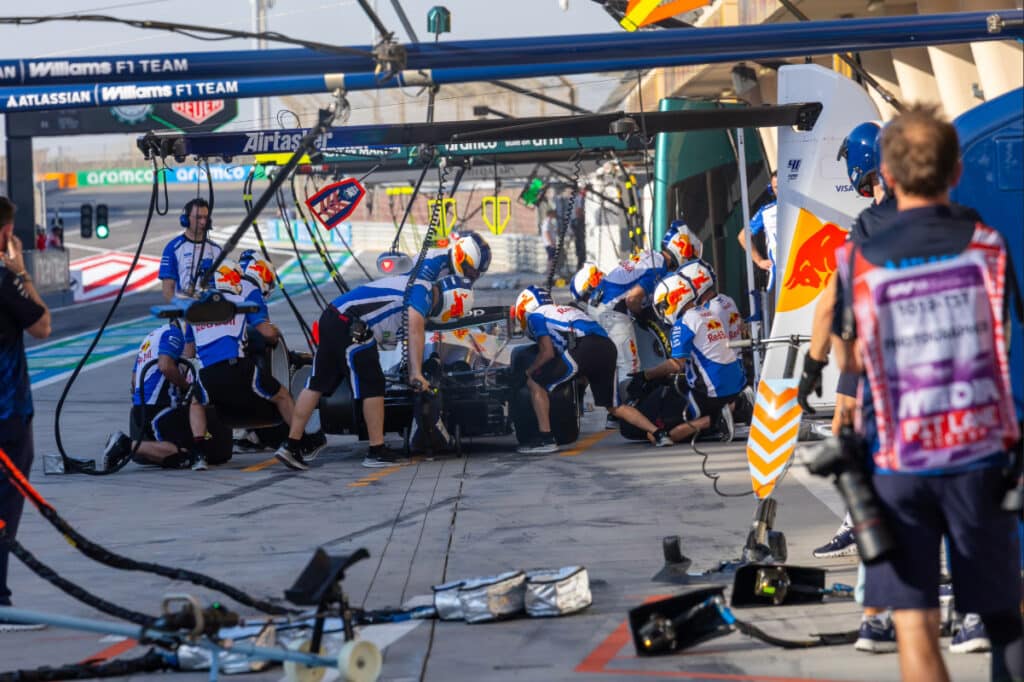The Visa Cash App RB (VCARB) pit crew performing high-pressure tire change drills under the afternoon sun in Bahrain.