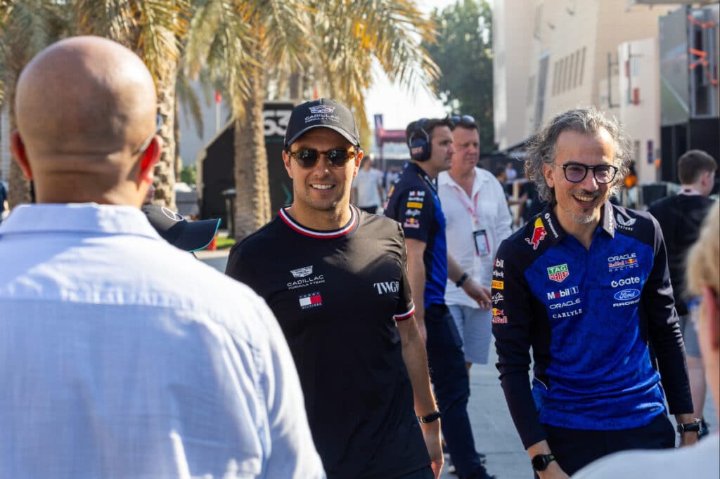 Sergio Perez smiling while walking through the Bahrain paddock in his Cadillac team gear, reflecting the positive trajectory of the new project after six days of testing.