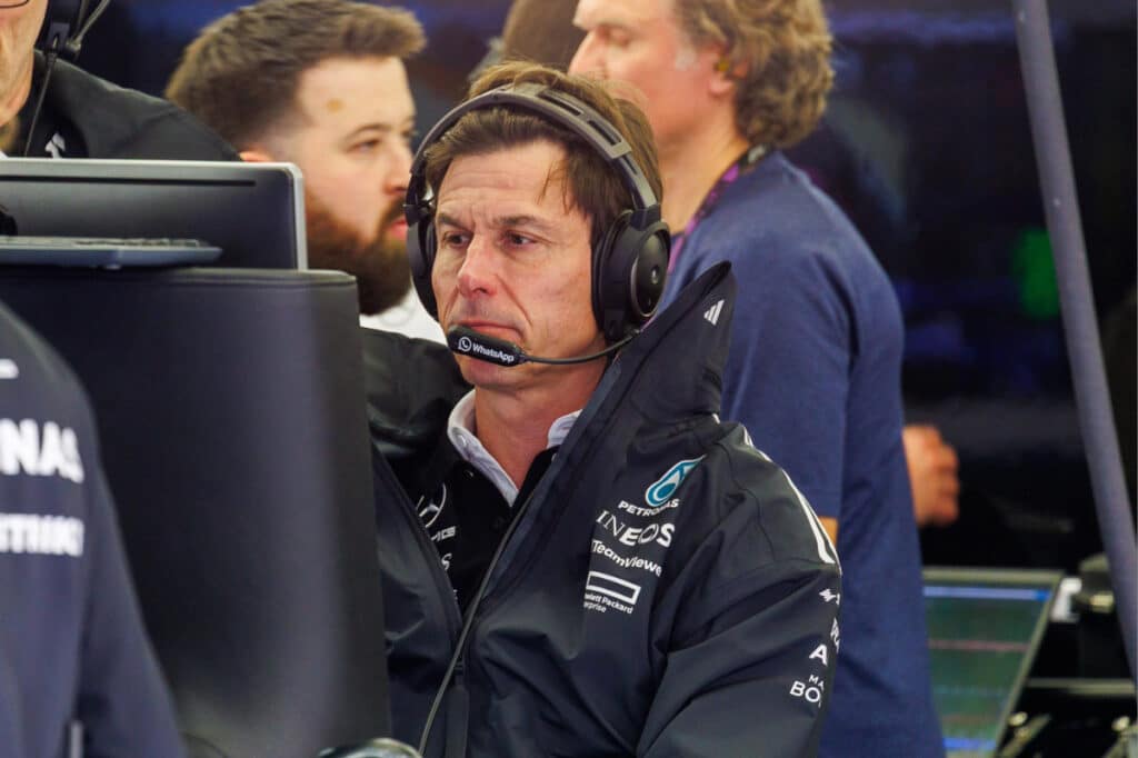 Mercedes Team Principal Toto Wolff wearing a headset on the pit wall, demonstrating focused leadership during a Formula One session.
