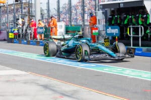 Aston Martin F1 car driving through the Albert Park pit lane during the Australian Grand Prix, representing the AMR26 technical challenges.