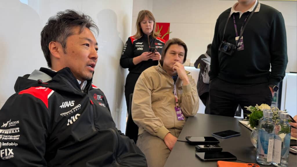 Haas Team Principal Ayao Komatsu leading a team briefing in the Haas TGR hospitality suite during the 2026 Chinese Grand Prix.