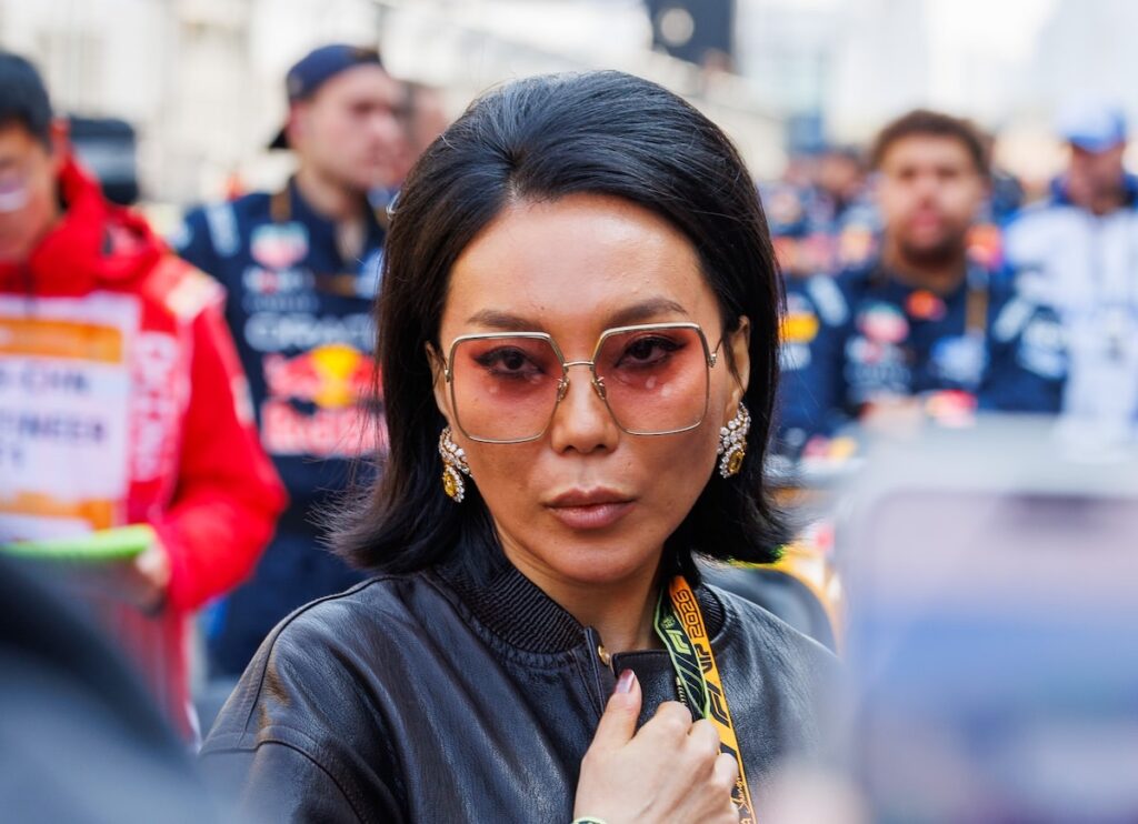 Chinese singer Bibi Zhou wearing oversized sunglasses and a black leather jacket in the F1 paddock during the 2026 Chinese Grand Prix.