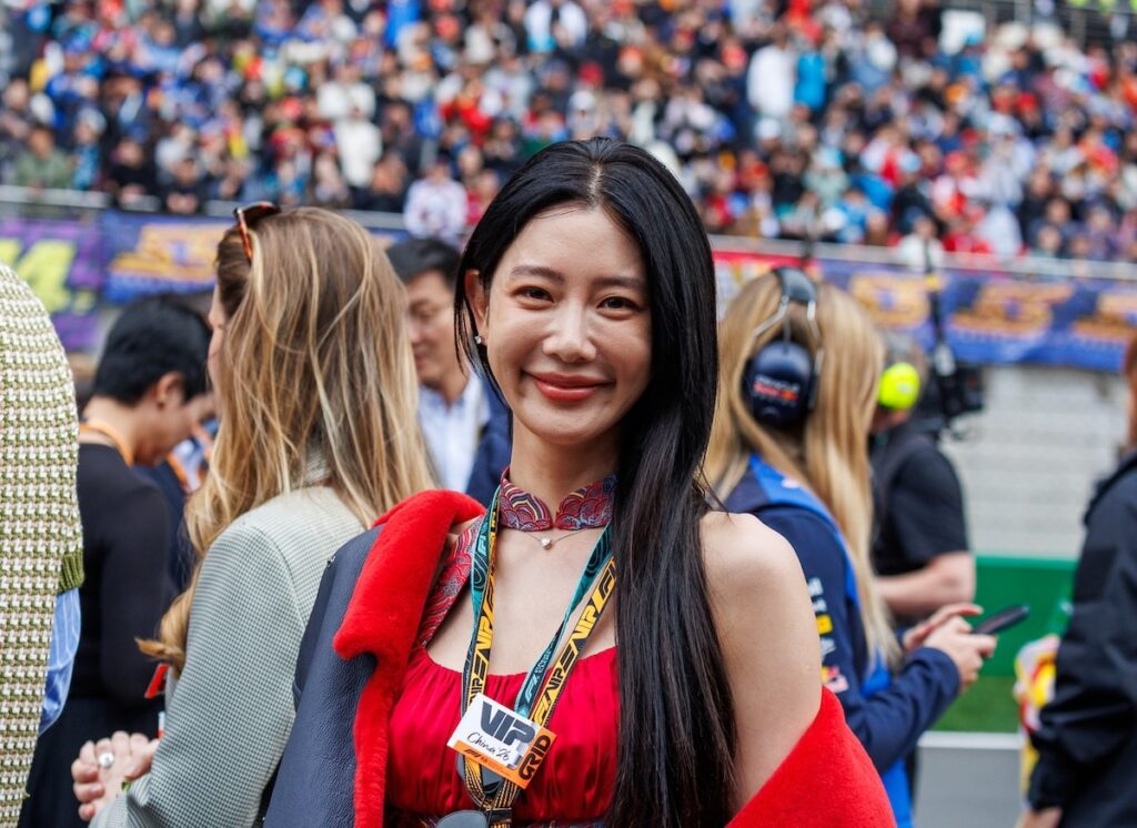 South Korean actress Clara Lee wearing a red dress and a Ferrari VIP pass at the 2026 F1 Chinese Grand Prix at the Shanghai International Circuit.