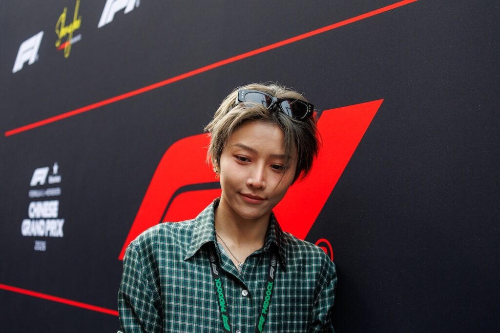 Chinese actress Crystal Zhang Tian’ai wearing a green plaid shirt and black sunglasses in the F1 paddock at the 2026 Chinese Grand Prix.