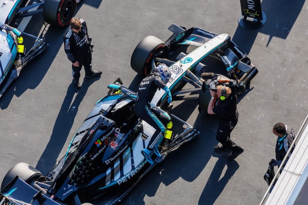 George Russell climbing out of his Mercedes W17 in the pit lane during a technical evaluation at the 2026 Chinese Grand Prix.
