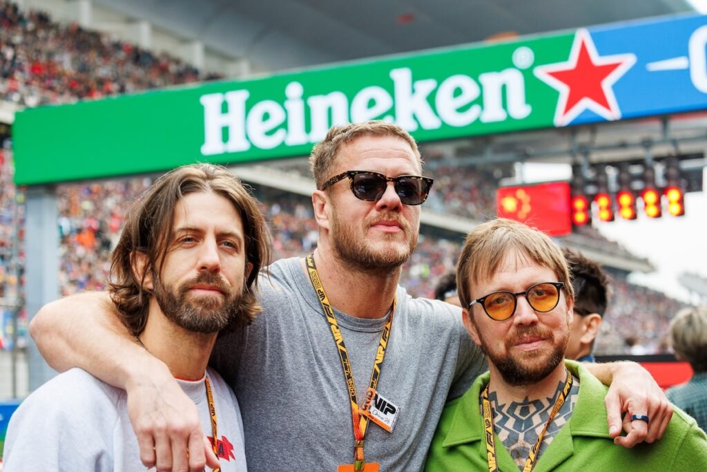 Dan Reynolds and members of Imagine Dragons posing together on the grid at the 2026 F1 Chinese Grand Prix in Shanghai.