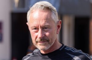 A close-up portrait of Jonathan Wheatley, formerly of Audi F1, looking thoughtful amidst intense speculation regarding his move to Aston Martin in 2026.