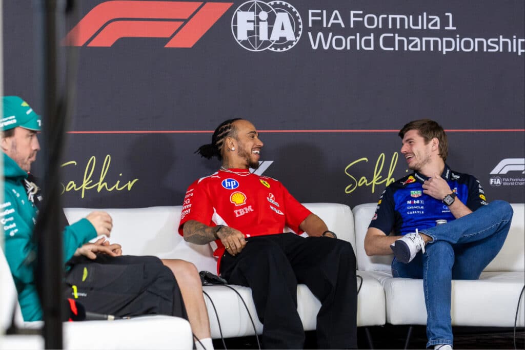 Lewis Hamilton in Ferrari red and Max Verstappen laughing together during the Thursday FIA press conference at the Australian Grand Prix.