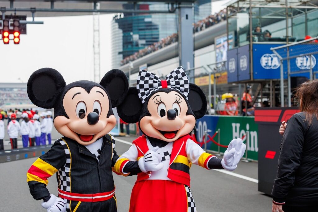 Mickey Mouse and Minnie Mouse in racing-themed outfits on the grid at the 2026 Chinese Grand Prix, representing Shanghai Disney Resort.